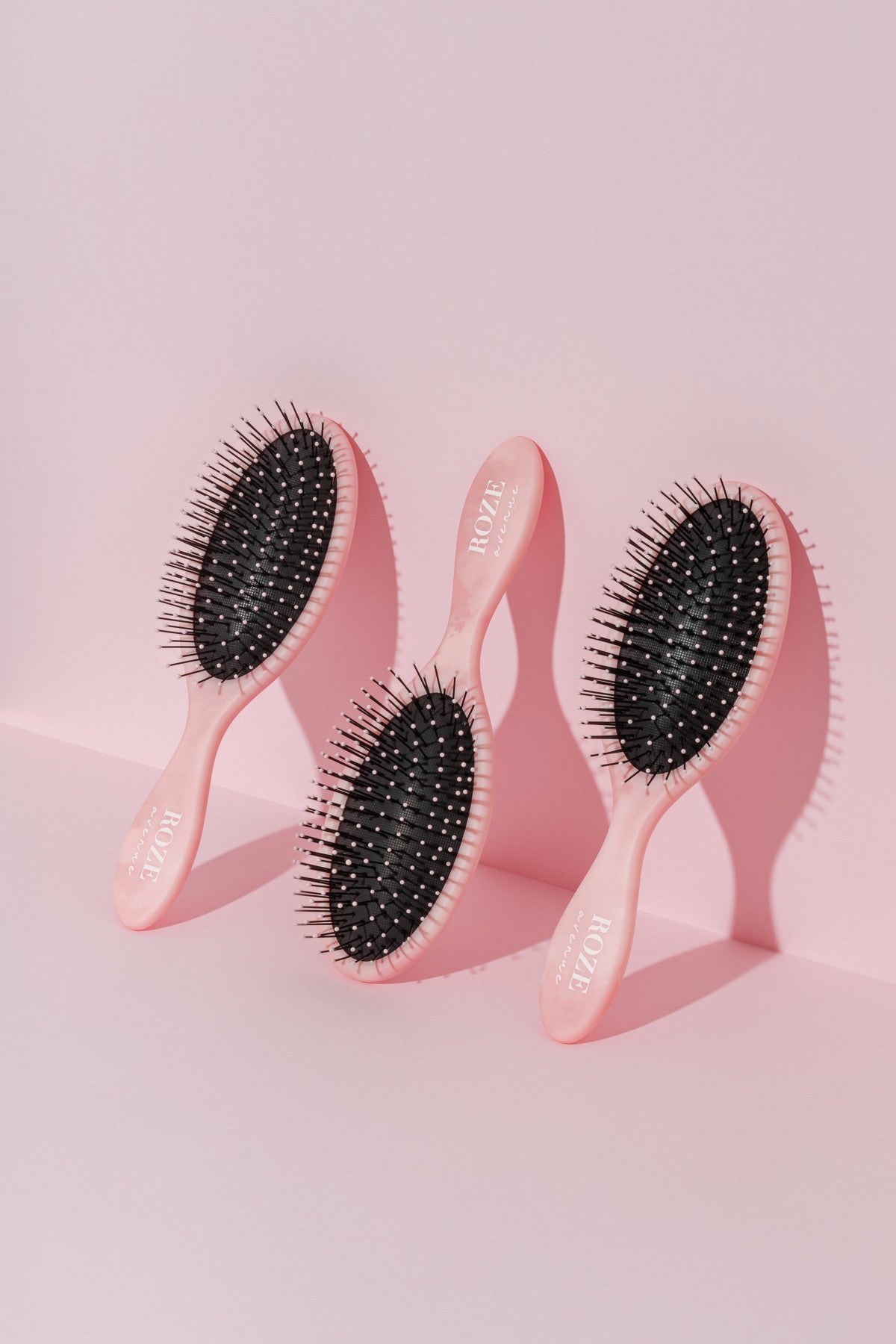 trzy szczotki do włosów Roze Avenue oparte o ścianę