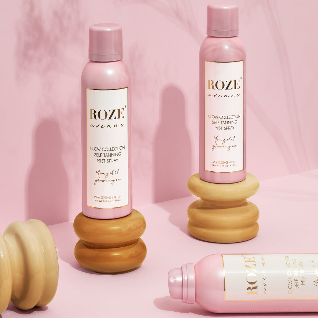 3 spraye samoopalacze roze avenue - dwa z nich stoją na drewnianych podkładkach, jeden z nich leży bez zakrętki