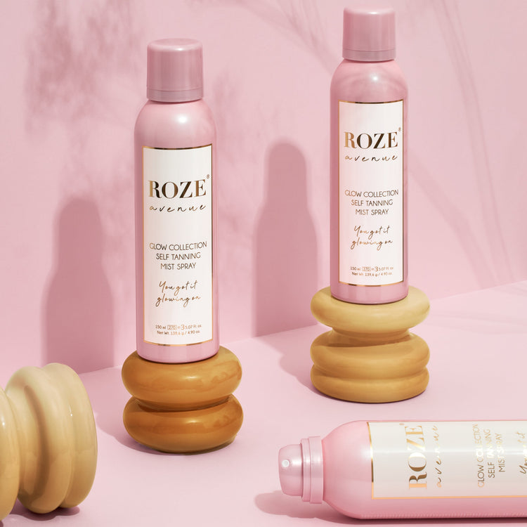 3 spraye samoopalacze roze avenue - dwa z nich stoją na drewnianych podkładkach, jeden z nich leży bez zakrętki